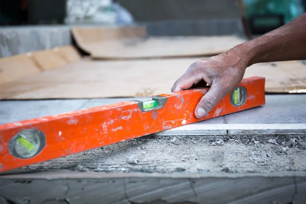 Trabajador exterior utilizando el nivel para la colocación de suelo de cemento — Foto de Stock