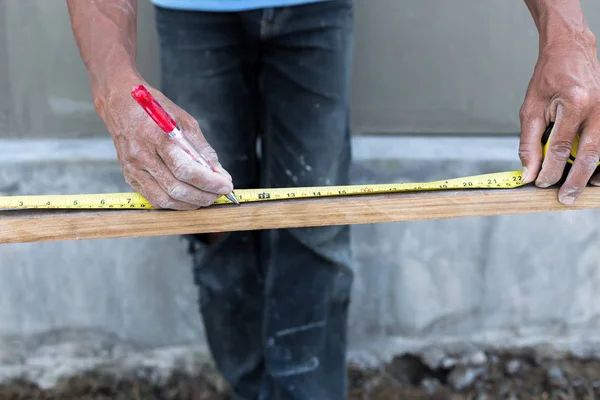 Carpenter ruka krejčovským metrem s červeným perem — Stock fotografie