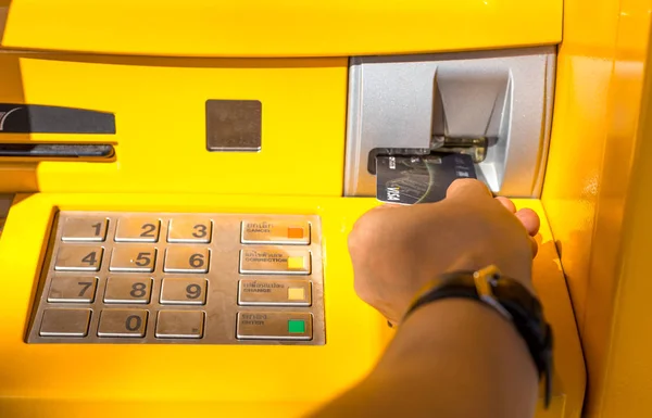 Mano insertando una tarjeta bancaria retirando dinero — Foto de Stock