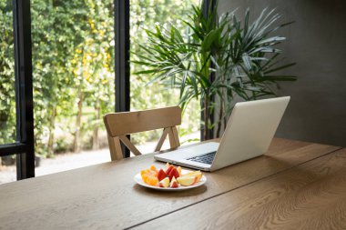 Taze meyve ve yeşil bitki ile dizüstü bilgisayar ile ahşap masa 