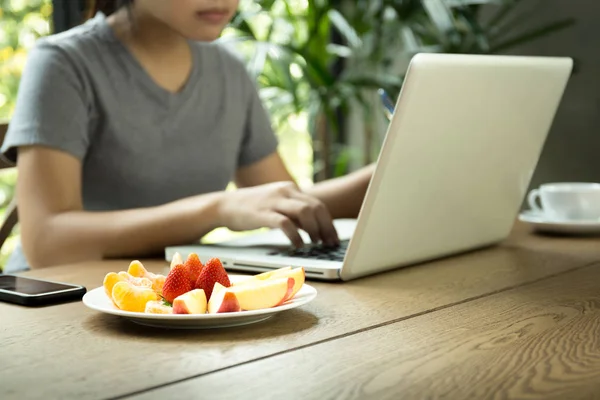 taze meyve ile dizüstü bilgisayar üzerinde çalışan genç Asyalı kadın çalışma 