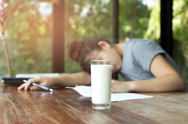 Ung kvinna falla sömn medan du läser en bok med glas mjölk — Stockfoto