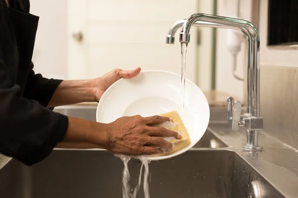 Woman washing the dishes in kitchen sink