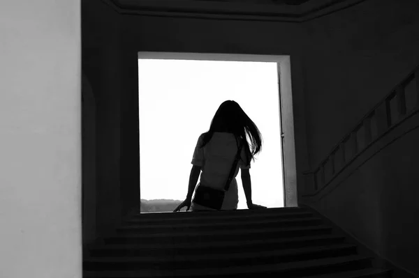 Silhueta adolescente menina sentado na porta passo pensando em preto e — Fotografia de Stock