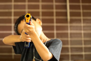 Küçük çocuk oyuncak silahla karşı oynarken 