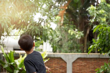 Küçük çocuk bahçesinde bir kağıt uçak ile oynarken 