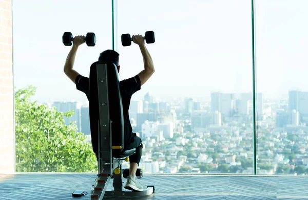 Man work out with dumbbells at the gym