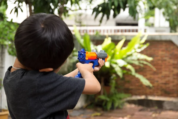 Küçük çocuk oyuncak silahla oynarken 