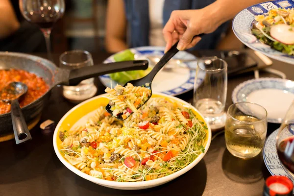 Familie middag hånd med stor ske spise pasta salat med kirsebær - Stock-foto