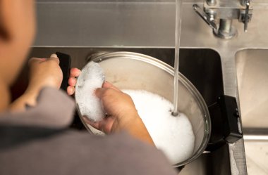 Kadın el yıkama bulaşık sabunu ile paslanmaz çelik tencere yıkama