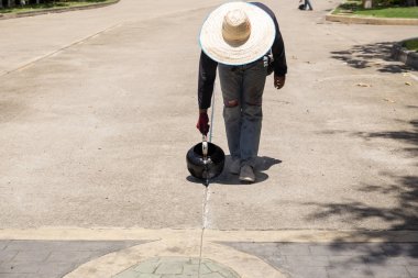 İşçi asfalt yol onarım için yağıyor 