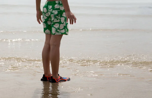 Little boy standing on the beach wearing aqua shoes — Stock Photo, Image