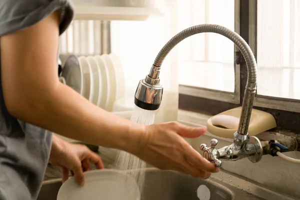 Donna trun su acqua di rubinetto lavare i piatti nel lavello della cucina — Foto Stock