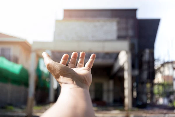 Mão conceitual chegando para casa no local de construção da casa — Fotografia de Stock