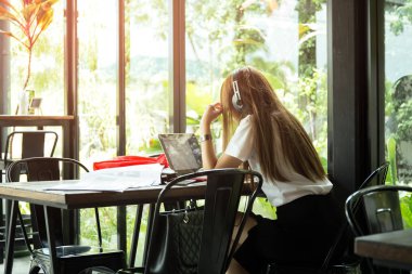 Asyalı öğrenci üniformalı kulaklık kafede eğitim ile