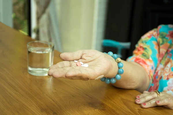 Concept de soins de santé femme âgée avec des pilules dans la main et glas — Photo