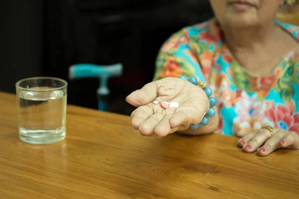 Концепция здравоохранения пожилая женщина с таблетками в руке и глазных яблок — стоковое фото