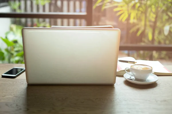 Portátil y taza de café y teléfono celular con libros y bolígrafo en wo — Foto de Stock