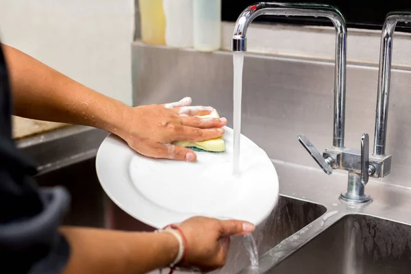 Donna mani lavaggio piatto bianco nel lavello della cucina — Foto Stock