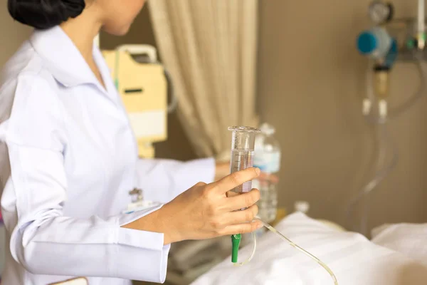 Enfermera dando agua al paciente usando jeringa de vidrio para irrigar nasog — Foto de Stock