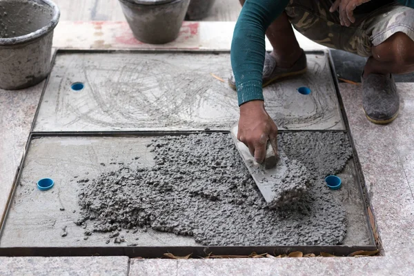Trabajador nivelación de cemento de manguera de drenaje con paleta — Foto de Stock
