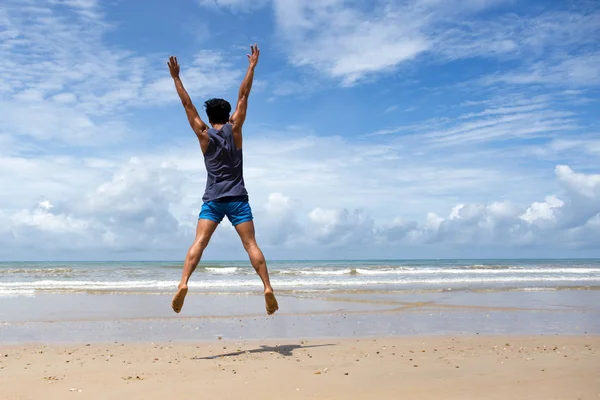 Homem feliz pulando na praia no céu azul — Fotografia de Stock