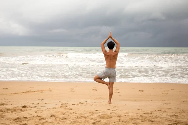 Hombre asiático haciendo yoga en la playa — Foto de Stock