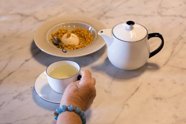 ชาตอนบ่าย มืออาวุโสถือถ้วยชาพร้อมหม้อชาและปู — ภาพถ่ายสต็อก