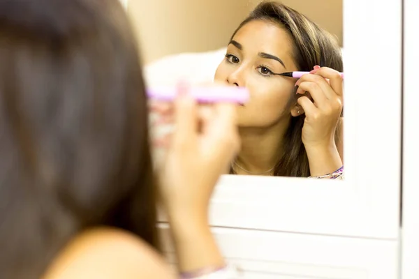 Mujer joven de raza mixta con cepillo delineador de ojos en la mirada en el mi — Foto de Stock