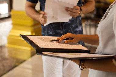 G ile konuşurken kayıt formu ile bir kalem tutan resepsiyonist