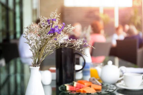 Flores roxas com salada de frutas na mesa de café da manhã — Fotografia de Stock