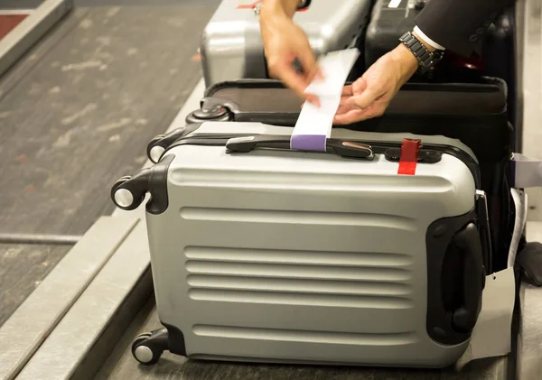 Check-in employee attaches a luggage tag to suitcase of passenge