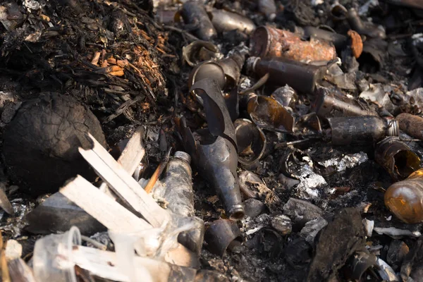 Broken glass bottles and garbage in burned trash — Stock Photo, Image