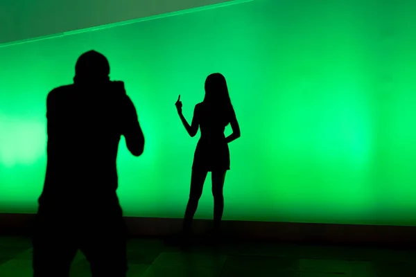 Silhouettes of people taking photo on colourful led screen