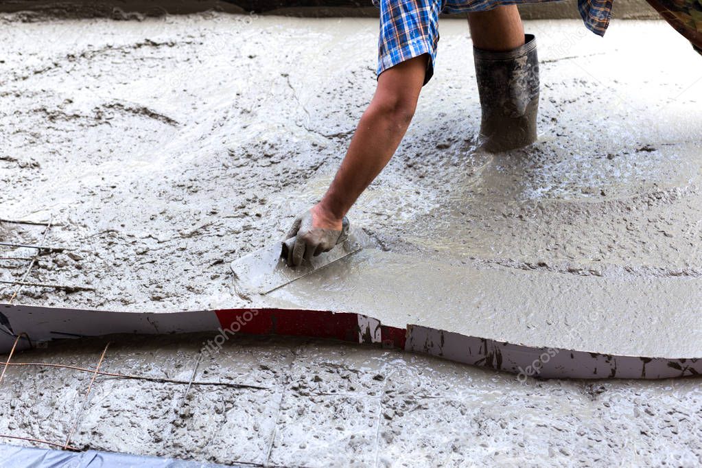 Construction worker spreading concrete during flooring 