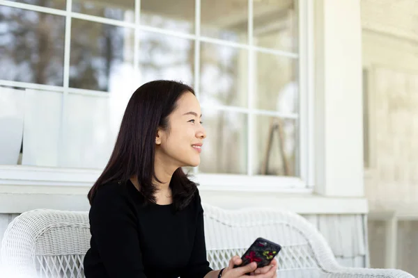 Mujer asiática sonriendo con la mano sosteniendo el teléfono celular —  Fotos de Stock