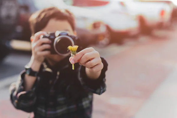 Niño tomando fotos de flor amarilla en su mano en vacaciones —  Fotos de Stock