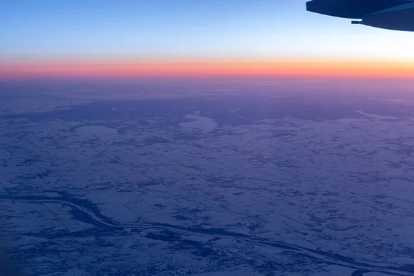 Vista aérea desde la ventana del avión sobre tierra con nieve — Foto de Stock