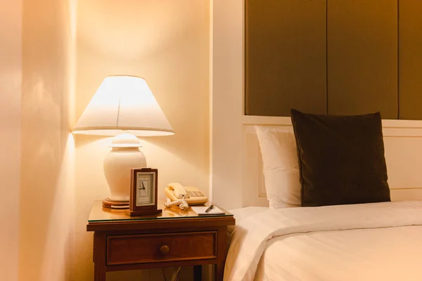 Camera da letto con lampada da lettura e orologio con telefono in hotel moderno . — Foto Stock