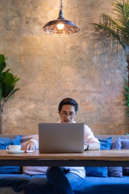 Kafede dizüstü bilgisayarda çalışan ve kahve fincanı olan bir adam..