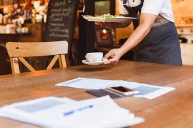 Garson restorandaki kirli tabakları kaldırıyor..