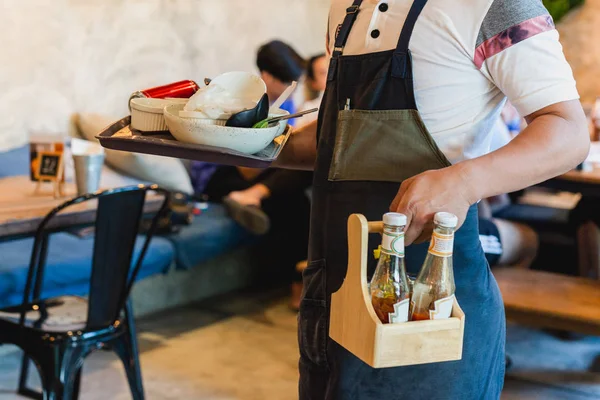 Kelner usuwający brudne naczynia ze stołów w restauracji. — Zdjęcie stockowe