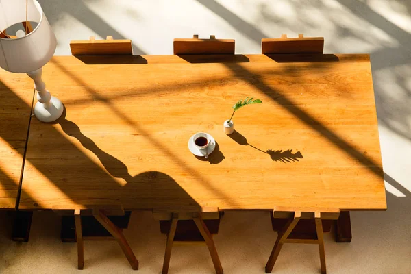 Bright room in the shadows of the sunlight with coffee on wooden table and lamp.