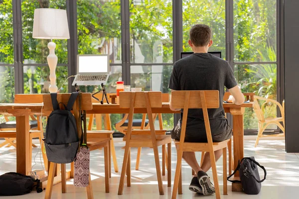 Человек в повседневной одежде сидит в кофейне и работает за ноутбуком . — стоковое фото