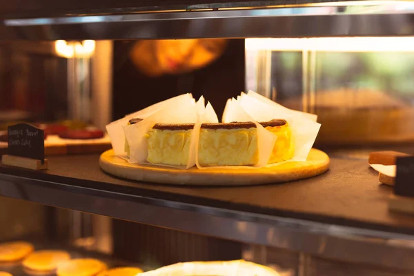 Baskischer verbrannter Käsekuchen in Tiefkühltruhe in Café mit Kellnerin im Hintergrund. — Stockfoto