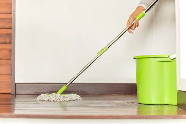 Die Hand der Frau hält einen Wischmopp, der den Fußboden des Hauses säubert. — Stockfoto