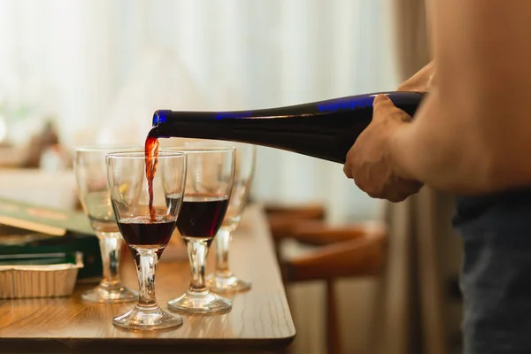 Mão derramando vinho tinto em vidro durante a festa com os amigos . — Fotografia de Stock