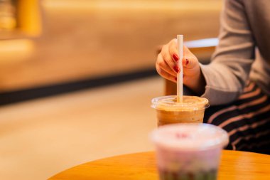 Plastik bardak soğuk kahvede kağıt kamışla kadın eli..