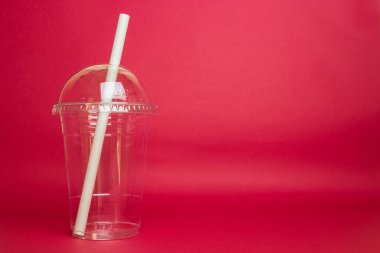 Kırmızı arkaplanda izole edilmiş kağıt kamışlı boş plastik parıltı.
