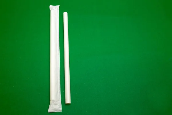 White packge paper straw isolated in green background.